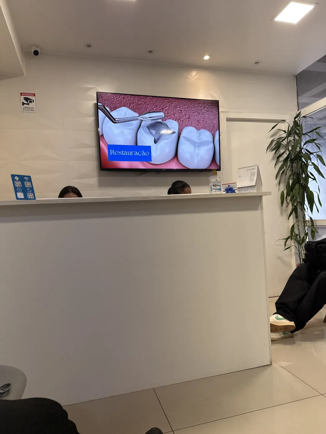 Recepção da Conic Odontologia com TV e balcão branco